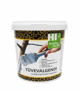 Viljapuude tüvevalgendi ämber ja valgendatud õunapuu tüvi päikeselisel talvepäeval